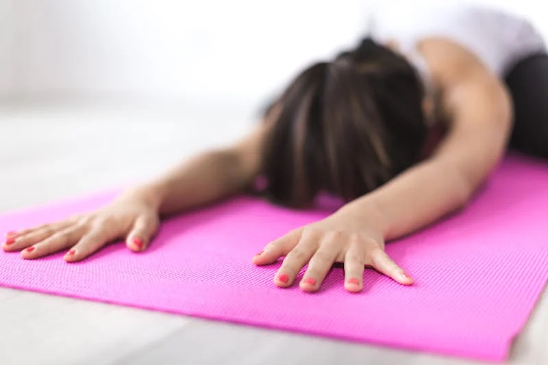 A woman in a calm yoga position on a beach at sunset